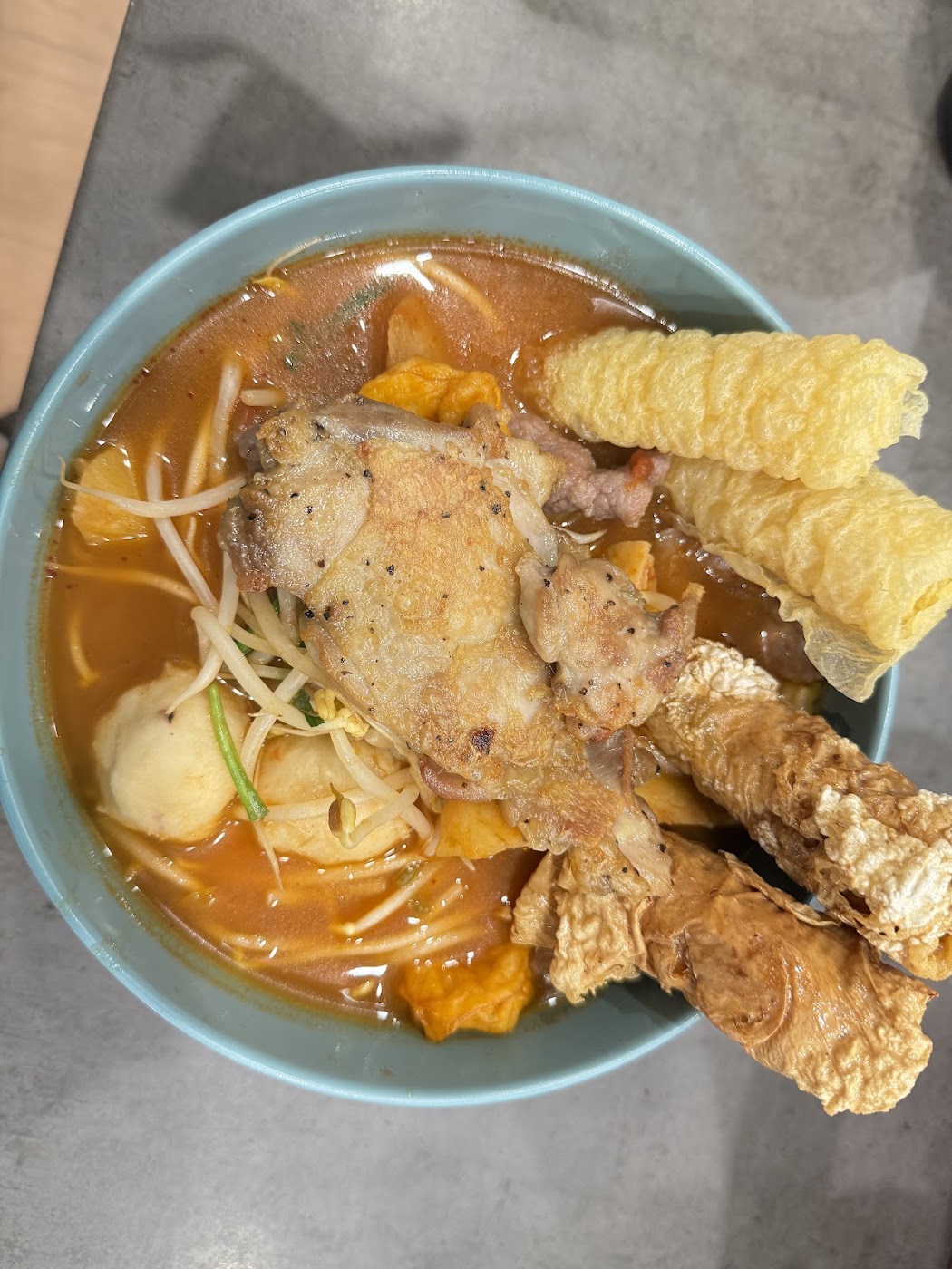 A bowl of Maiseen Kong mixian — rice noodles in tomato broth with fried beancurd, beansprouts and toppings